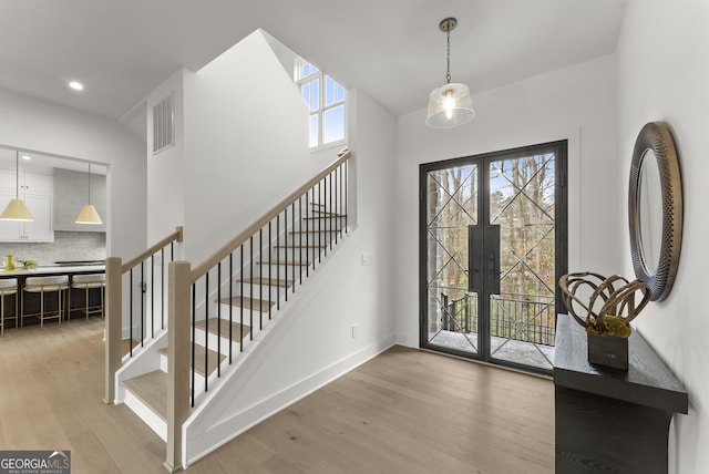 entryway featuring stairs, light wood-type flooring, visible vents, and baseboards