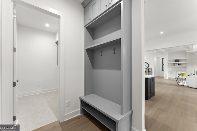 mudroom with baseboards, recessed lighting, wood finished floors, and built in features