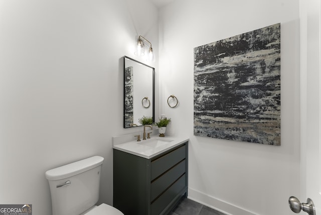 half bathroom featuring toilet, baseboards, and vanity