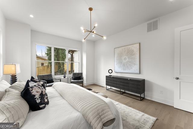 bedroom with light wood-style floors, visible vents, a notable chandelier, and baseboards