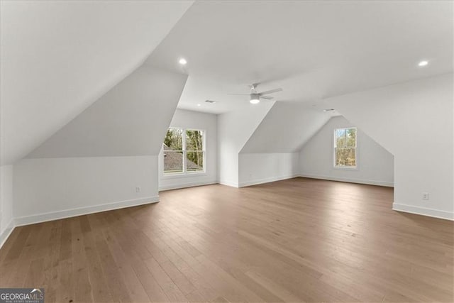 additional living space featuring ceiling fan, wood-type flooring, a healthy amount of sunlight, and vaulted ceiling