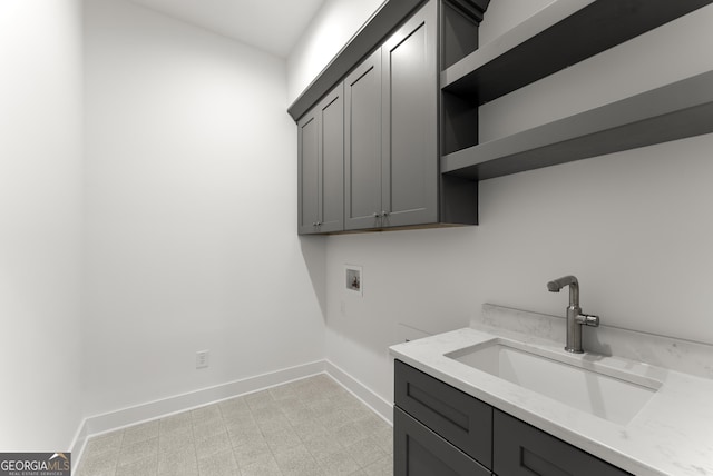 laundry area featuring cabinet space, baseboards, hookup for a washing machine, light floors, and a sink