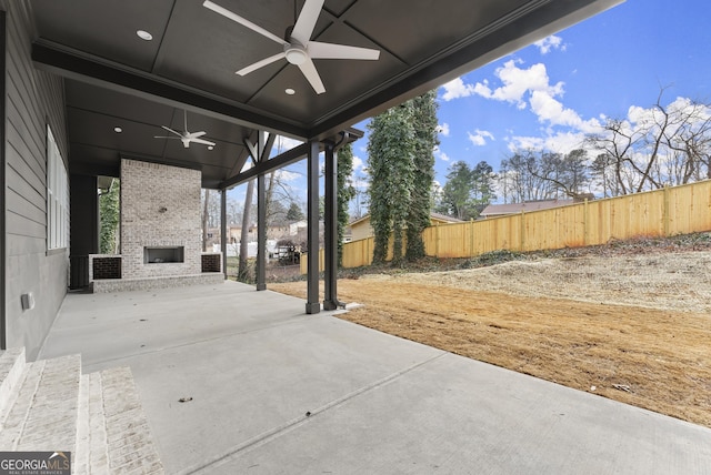 view of patio / terrace with a large fireplace, a fenced backyard, and ceiling fan