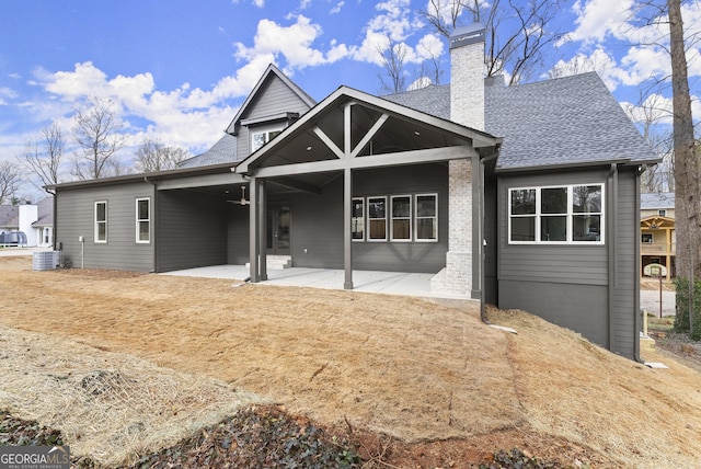 back of house featuring a shingled roof, a chimney, a patio area, and cooling unit