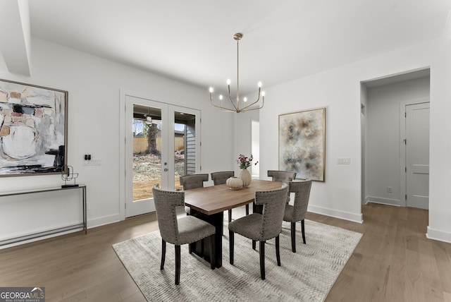 dining room with baseboards, french doors, wood finished floors, and a notable chandelier