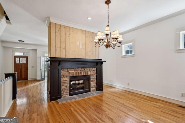 unfurnished living room featuring an inviting chandelier, ornamental molding, a fireplace, and hardwood / wood-style floors