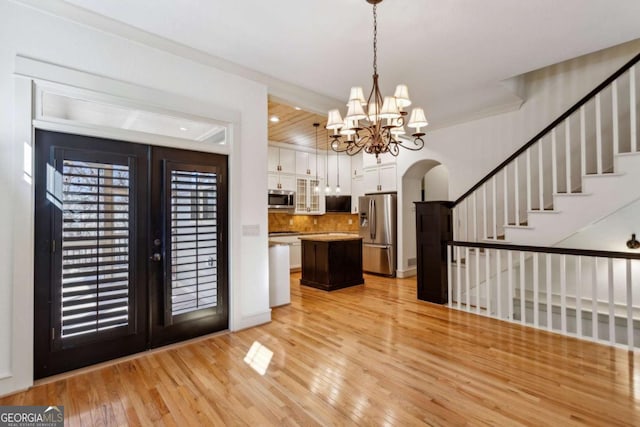 kitchen with a center island, appliances with stainless steel finishes, pendant lighting, light hardwood / wood-style floors, and white cabinets