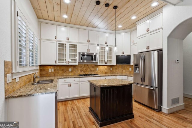 kitchen featuring sink, white cabinetry, appliances with stainless steel finishes, a kitchen island, and pendant lighting