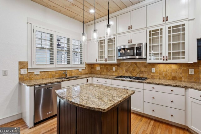 kitchen featuring appliances with stainless steel finishes, pendant lighting, tasteful backsplash, sink, and a center island