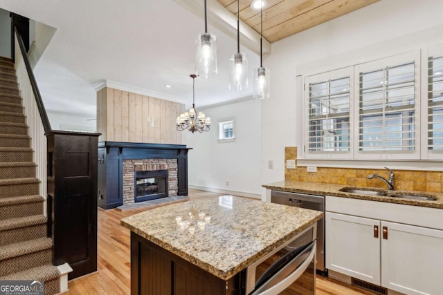 kitchen with sink, dishwashing machine, pendant lighting, light stone countertops, and white cabinets