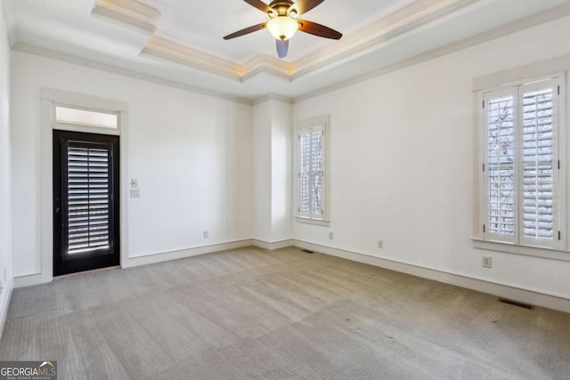 carpeted spare room featuring a raised ceiling, ornamental molding, and ceiling fan