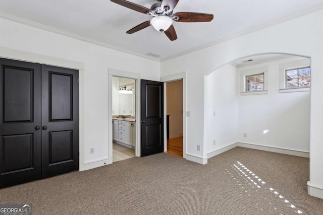 unfurnished bedroom featuring light carpet, crown molding, and ceiling fan