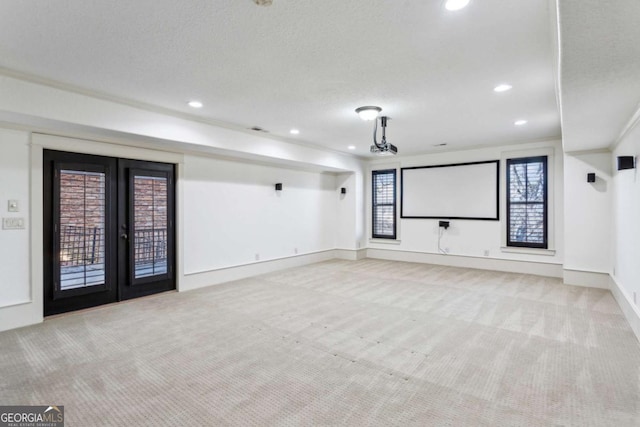 carpeted home theater room featuring french doors and a textured ceiling