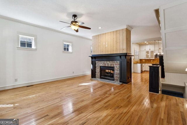 unfurnished living room featuring a fireplace, light hardwood / wood-style floors, ceiling fan, and plenty of natural light