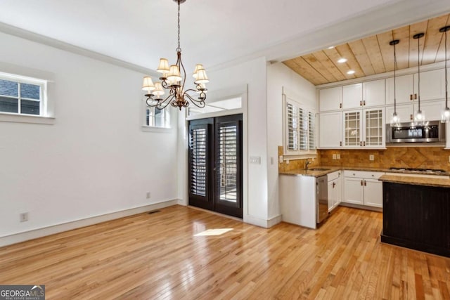 kitchen with sink, white cabinetry, stainless steel appliances, tasteful backsplash, and decorative light fixtures