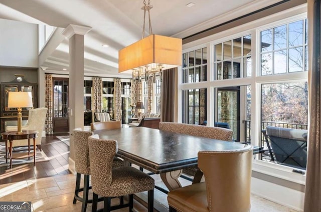 dining room featuring ornate columns, a healthy amount of sunlight, and a chandelier