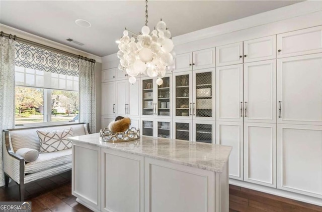 kitchen with white cabinetry, dark hardwood / wood-style floors, light stone countertops, decorative light fixtures, and a chandelier