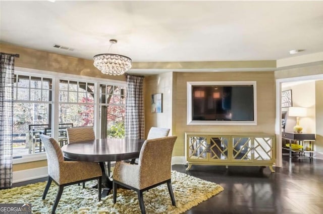 dining space featuring a notable chandelier and dark parquet floors