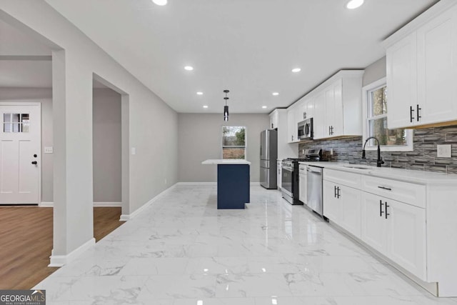 kitchen featuring sink, stainless steel appliances, a center island, white cabinets, and decorative backsplash