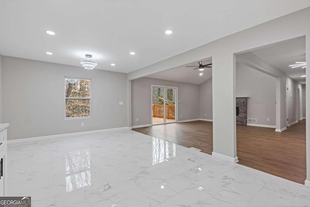 unfurnished living room with a stone fireplace, vaulted ceiling, and ceiling fan