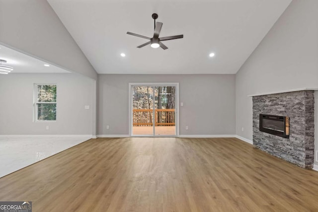 unfurnished living room featuring ceiling fan, high vaulted ceiling, a fireplace, and light hardwood / wood-style floors