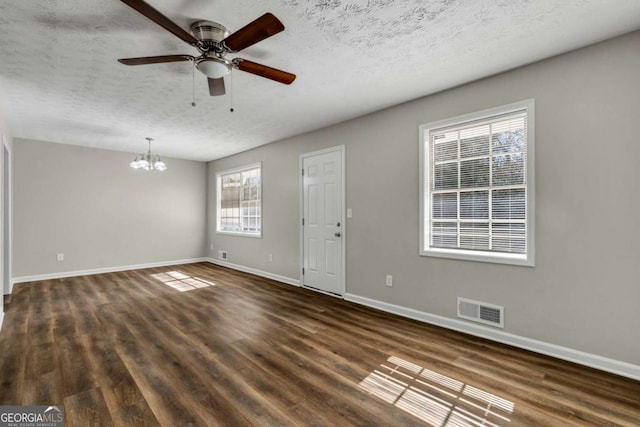 spare room featuring dark wood-type flooring, ceiling fan with notable chandelier, and a textured ceiling