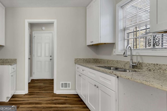 kitchen with dark hardwood / wood-style flooring, sink, white cabinets, and light stone counters