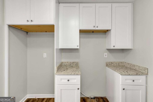 kitchen with light stone counters, white cabinetry, and dark wood-type flooring