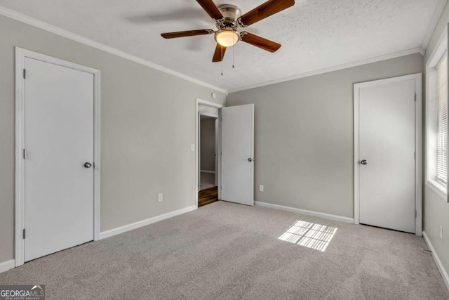 unfurnished bedroom featuring light carpet, ceiling fan, ornamental molding, and a textured ceiling