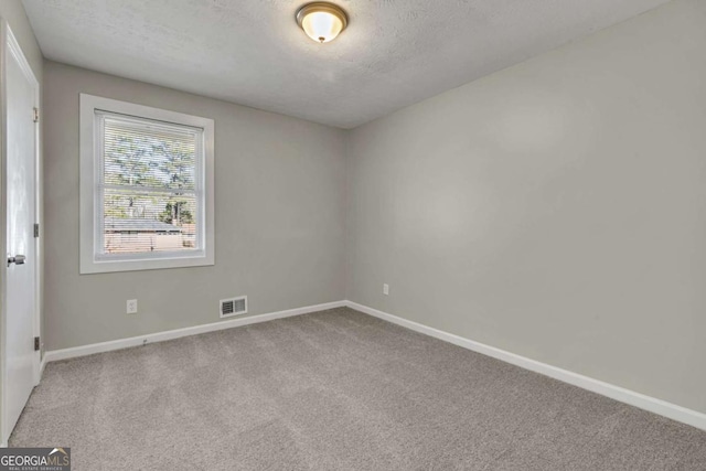 spare room with light carpet and a textured ceiling