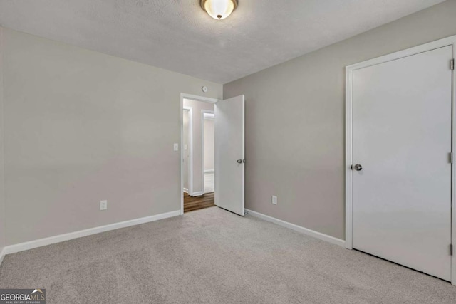 unfurnished bedroom featuring light carpet and a textured ceiling