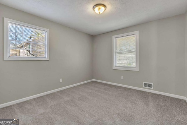 carpeted empty room with a textured ceiling