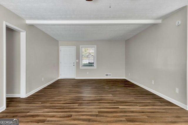 spare room with beam ceiling, dark hardwood / wood-style flooring, and a textured ceiling