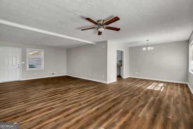 unfurnished living room featuring a healthy amount of sunlight, ceiling fan with notable chandelier, dark hardwood / wood-style floors, and a textured ceiling