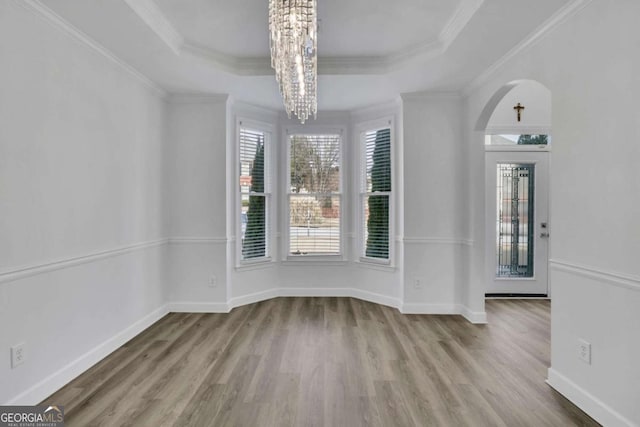 interior space featuring a raised ceiling, ornamental molding, and hardwood / wood-style flooring