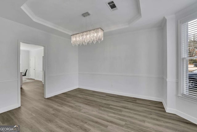 unfurnished room with crown molding, dark hardwood / wood-style flooring, a raised ceiling, and a chandelier