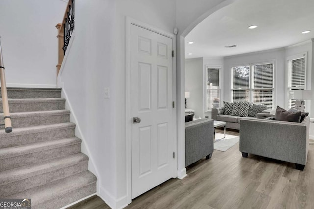 stairway with hardwood / wood-style flooring and crown molding