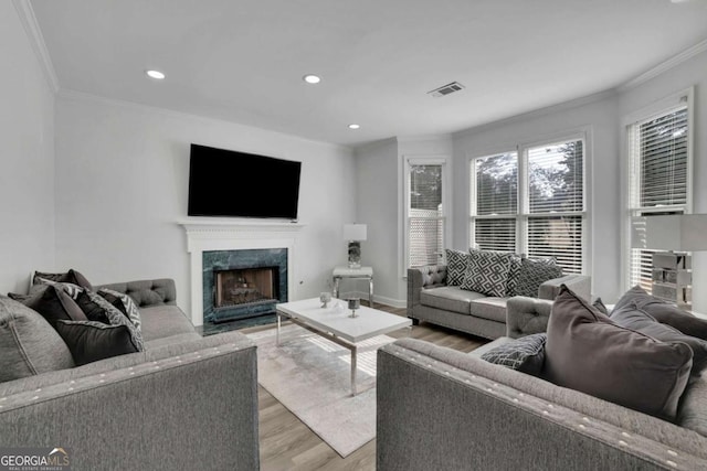 living room featuring ornamental molding, a fireplace, and light hardwood / wood-style floors