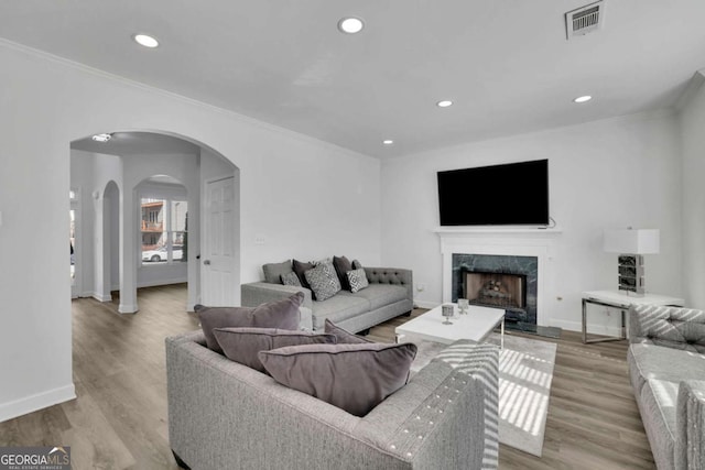 living room with ornamental molding, a fireplace, and light hardwood / wood-style floors