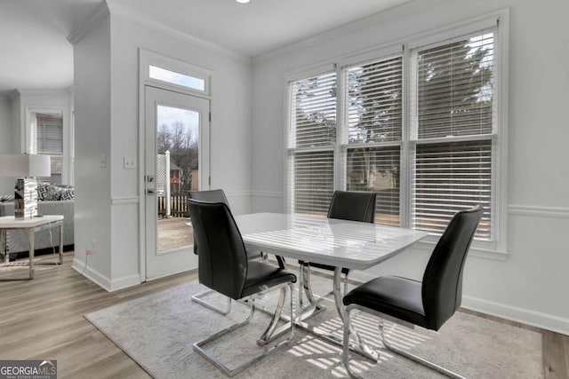 dining area with light hardwood / wood-style flooring and ornamental molding