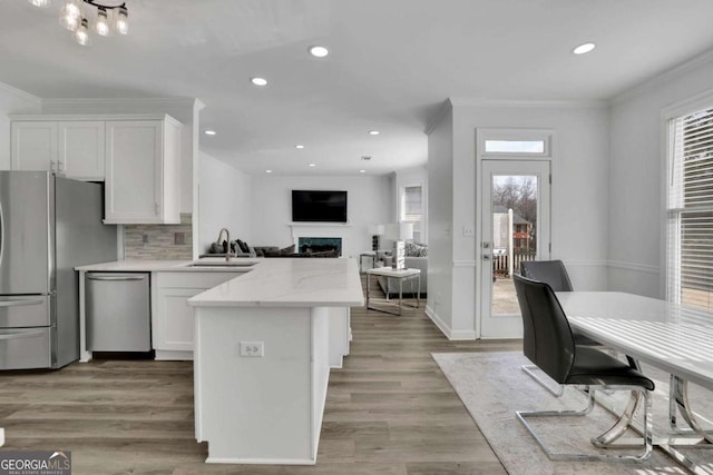 kitchen with stainless steel appliances, white cabinetry, sink, and light stone counters