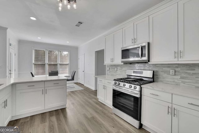 kitchen with tasteful backsplash, white cabinets, light hardwood / wood-style floors, stainless steel appliances, and light stone countertops