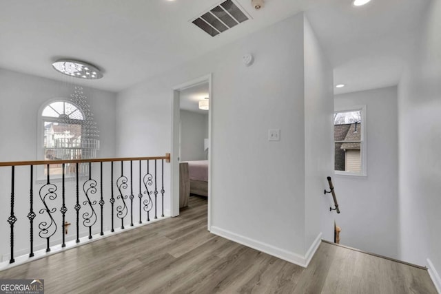 hallway with an inviting chandelier and light wood-type flooring