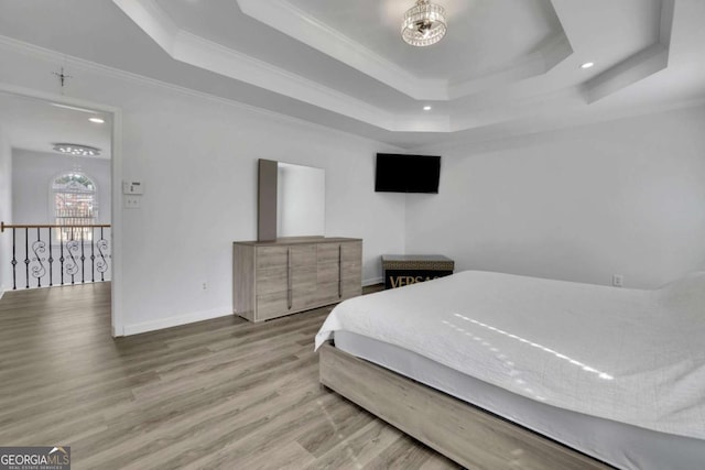 bedroom with a raised ceiling, wood-type flooring, crown molding, and an inviting chandelier