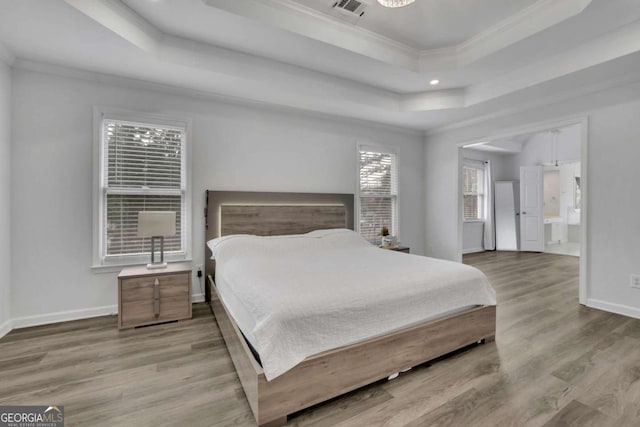 bedroom featuring crown molding, a raised ceiling, and light hardwood / wood-style flooring