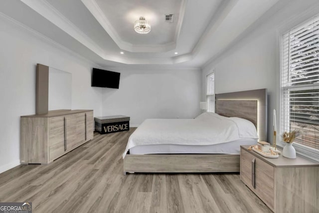 bedroom featuring a raised ceiling, crown molding, and light hardwood / wood-style flooring