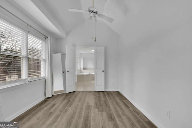 unfurnished bedroom with ensuite bathroom, lofted ceiling, and light wood-type flooring