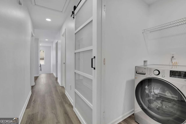 washroom featuring washer / clothes dryer, wood-type flooring, and a barn door