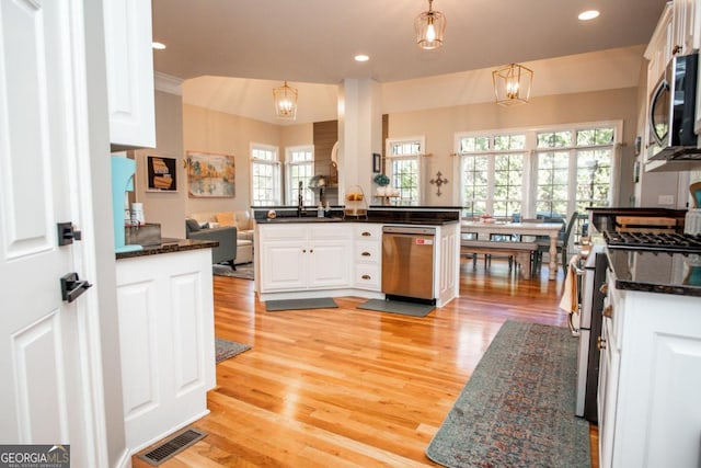 kitchen featuring white cabinetry, hanging light fixtures, stainless steel appliances, and kitchen peninsula