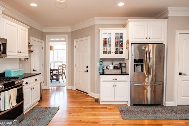 kitchen featuring stainless steel appliances, crown molding, white cabinets, and light wood-type flooring